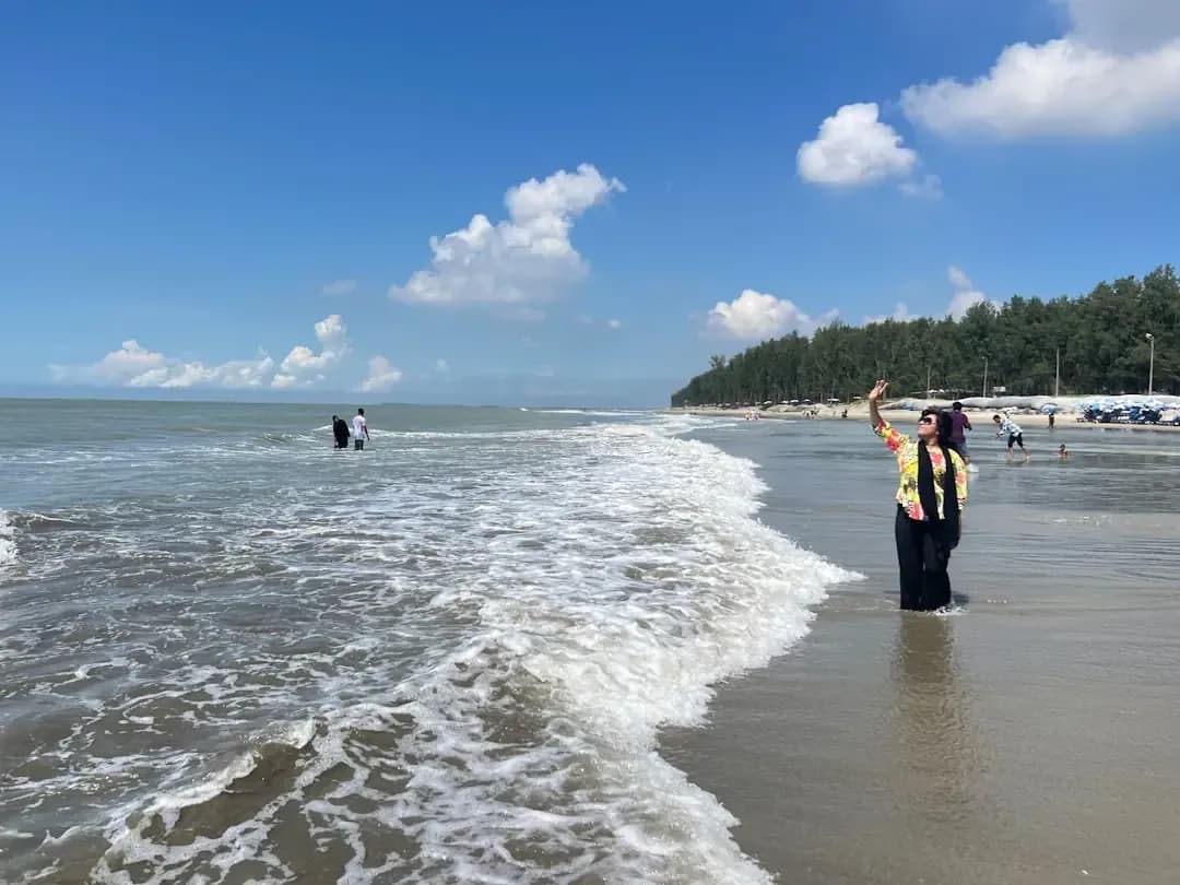 A man standing on top of a sandy beach next to the ocean