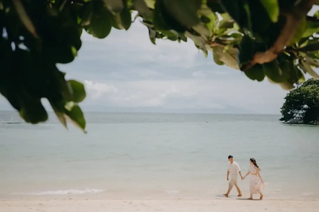 Couple holding hands walking on a tropical beach.