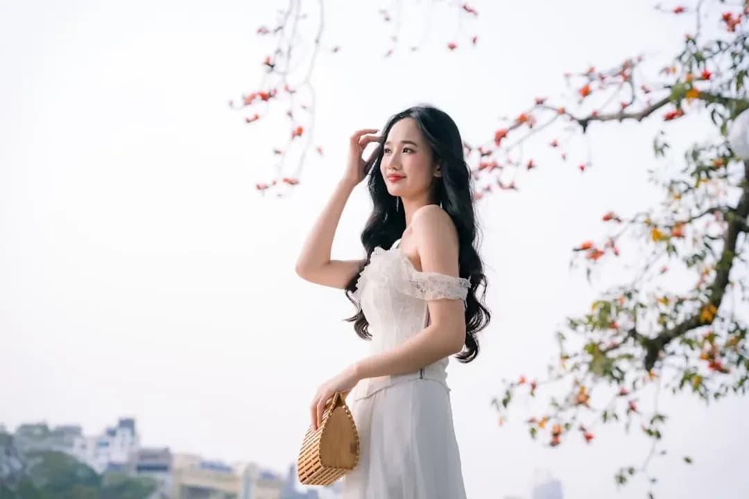 Young woman in white dress with flowers in background