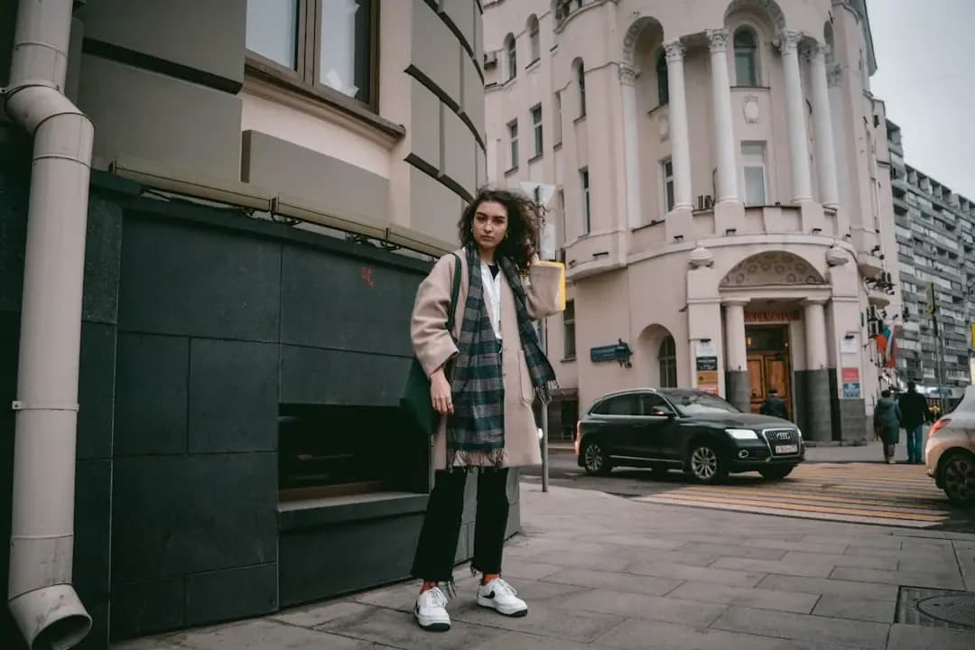 woman in black and white plaid coat standing on sidewalk during daytime