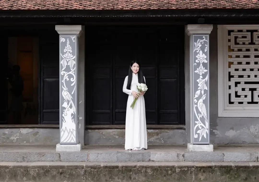 A woman in a white dress standing in front of a building