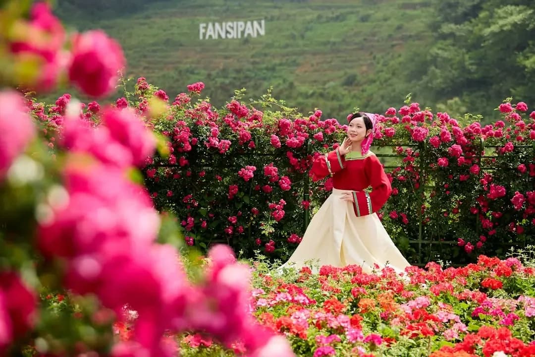 Woman in traditional dress poses in a rose garden.