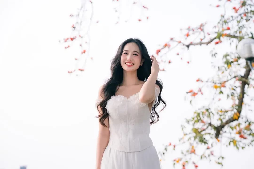 A smiling woman in a white dress outdoors
