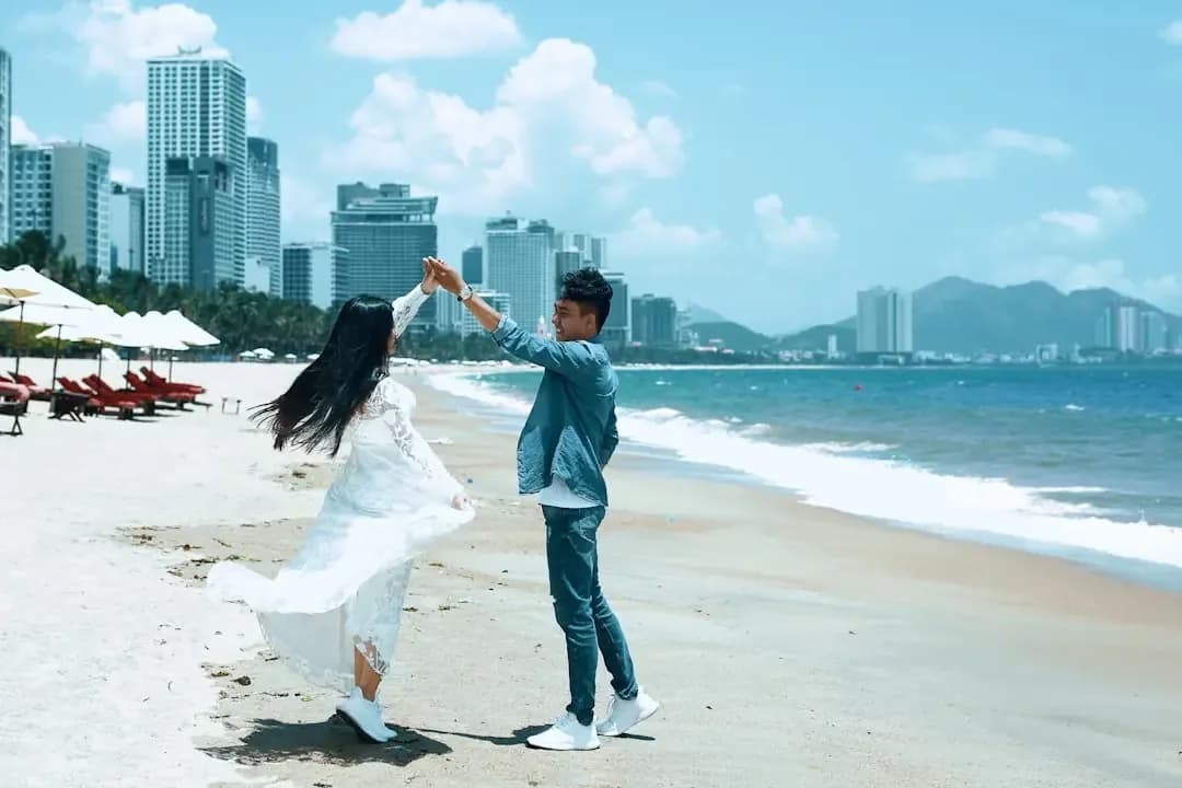 a man and woman standing on top of a sandy beach